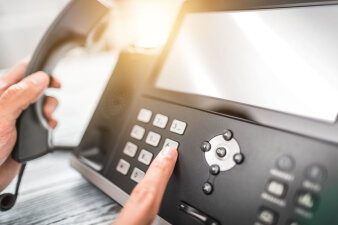 Hand hebt Hörer von Telefon und Finger tippt